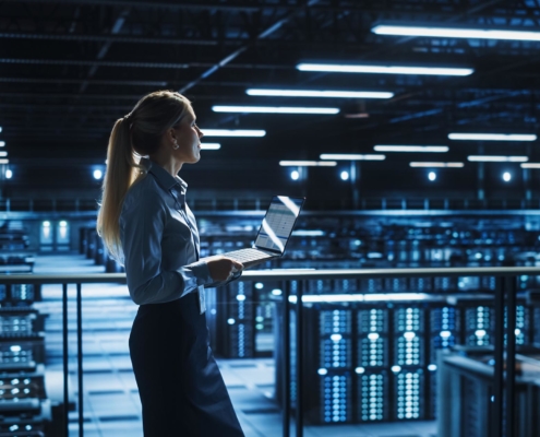 Image of a person walking through a data center with a laptop.
